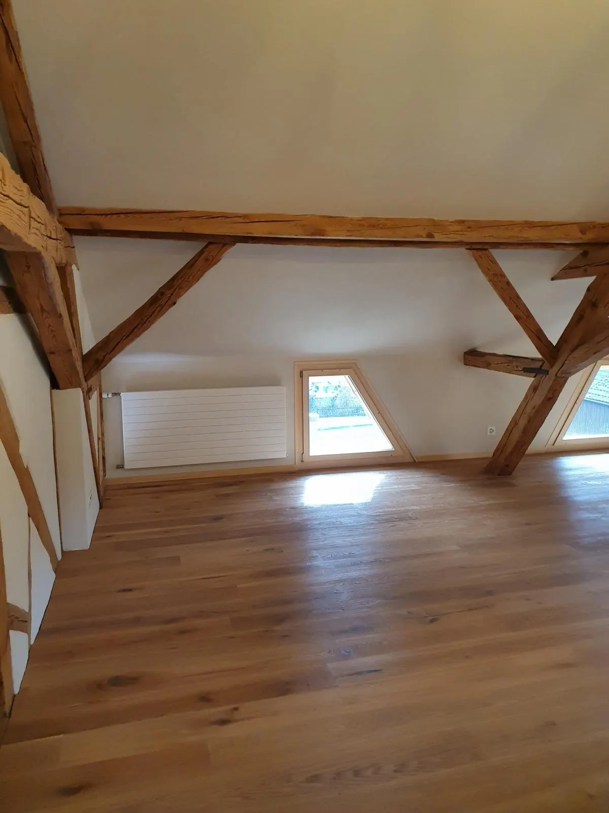 Referenzobjekt — Dachausbau mit sichtbaren Holzbalken und neuen Wandflächen